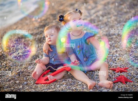 Brother And Sister Playing In The Shore Break On The Beach During The Hot Summer Vacation Day