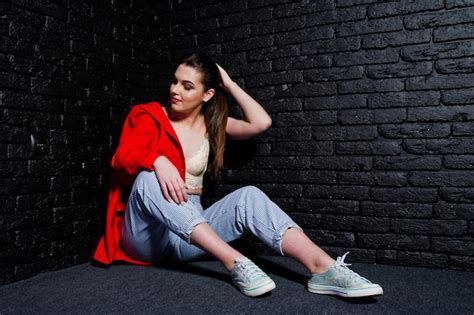 Free Photo Stylish Brunette Girl On Red Jacket Against Studio Black Brick Wall
