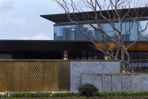 A Building With A Tree In Front Of It Next To A Fence And Shrubbery