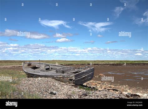 Side View Of Old Wooden Boat Wrecked And Stranded On A Rocky Shoreline