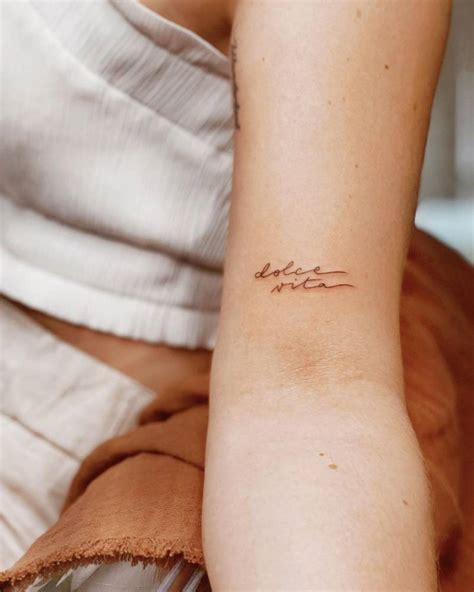 "Dolce Vita" lettering tattoo handwritten on the bicep.