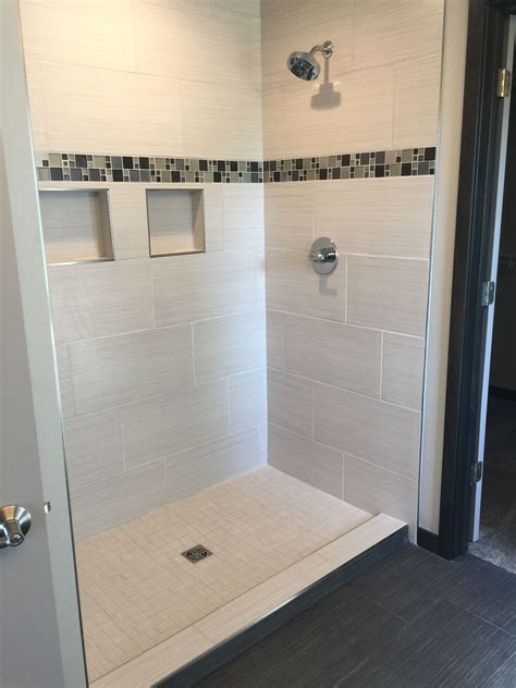How do you designers suggest placing tiles on the floor or wall ? For a small monochromatic bathroom scheme, 12x24 gray tiles of different shades and textures, should they be placed in brick pattern? On the floor, vertically on the shower walls? I do have a vertical stripe of accent tile on one of the walls. Shower pan would be mosaic 2x2 tiles.. 