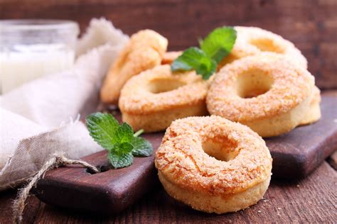 rosquinhas de creme de leite assadas Em uma tigela, coloque o açúcar, a margarina, os ovos e mexa bem com o auxílio de um fouet; Adicione o creme de leite e o leite e misture bem; Vá adicionando a farinha de