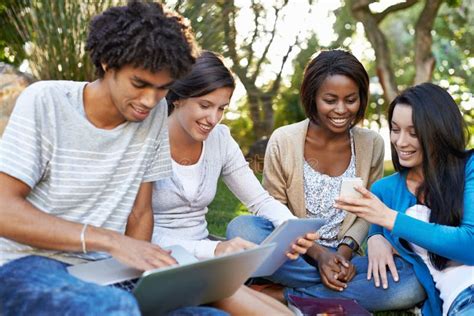 A Group of Students Sit Together Using a Tablet and a Book To St Stock