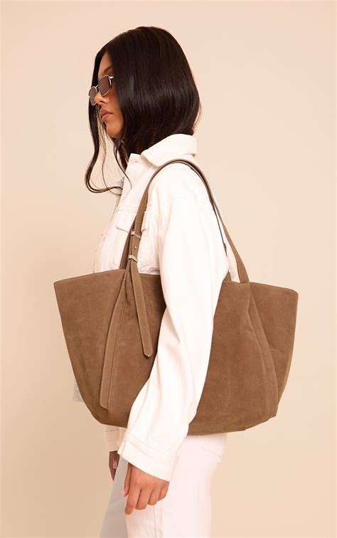 Adjustable strap for bag.  Made from a tan faux suede material, this tote features ...