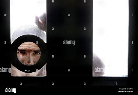 An inmate peers through a peep hole while in the exercise yard in