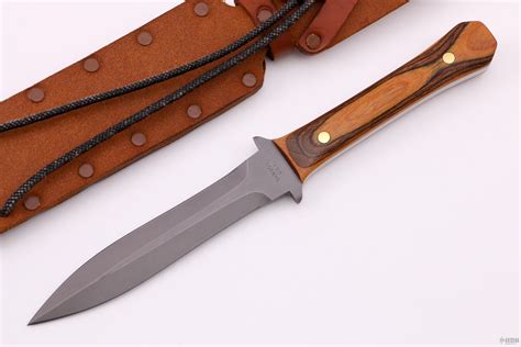 Custom hunting knife produced by traditional methods of metalwork and decoration: blade grinding, hand engraving, polishing. Fixed blade knife. Blade of Bohler N695 steel, spear point shaped. Handle of assembled metal and wooden parts. Titanium square bolster with fine and profound leaves engravings. Ebony wooden grip with two decorative rivets.. 