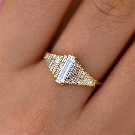 Baguette cut diamond. This dazzle centerpiece is guarded on each side with a geometric diamond-set band, creating an impressive three-in-one effect. 1.46 carat total diamond weight. 