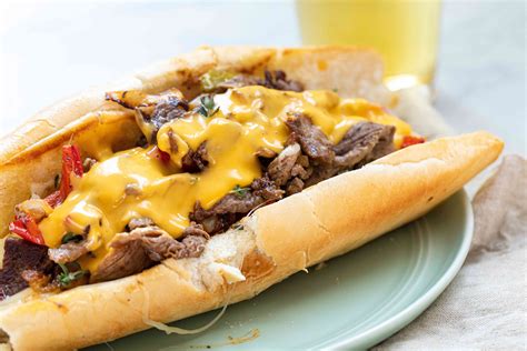 Best cheese for cheesesteak. Preheat the oven to 375F. Line a baking sheet with parchment paper or foil put partially split sandwich rolls on the baking sheet and set aside. Thinly slice the steak and also slice the onions, peppers, and mushrooms. Heat the olive oil in a large skillet over medium-high heat. 