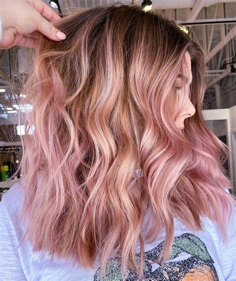 Blonde hair with brown and pink highlights. Pink highlights can instantly transform your look for different types of bangs, including blunt, wispy, side-swept, or asymmetrical bangs. From soft pastel shades to vibrant neon hues, the options for pink colored bangs are endless. Pink bangs add a playful and youthful touch to any hairstyle. via @bel_pipsqueekinsaigon. 