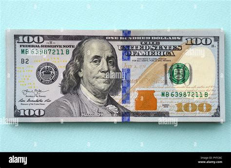 Blue stripe on 100 dollar bill. One hundred hundred-dollar bills are delivered by Federal Reserve Banks in mustard-colored straps ($10,000). The Series 2009 $100 bill redesign was unveiled on April 21, 2010, and was to be issued to the public in February 11, 2011, but production was shut down in December 2010 because as many as 30% were unusable due to a manufacturing flaw. 