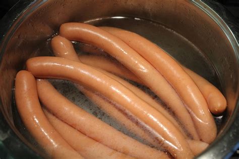 Boiling hot dogs. To boil hot dogs in beer, add around two or three cans to a pan, bring it to a boil, and then simmer uncovered for around five minutes or until heated through, before draining and serving. While ... 