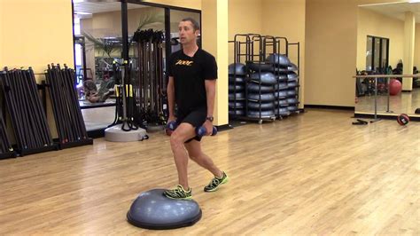 How to do BOSU Ball Weighted Squat: Step 1: Place the BOSU ball on the ground (either side up). Step 2: Take a dumbbell in each hand. Step 3: Step up on the BOSU ball with your feet 4-6 inches apart. Step 4: Bend at the knees and squat downwards till your knees make about a 90 degree angle and then stand back up. Step 5: This completes one repetition.. 