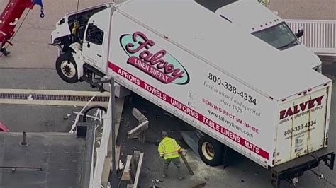 Box truck dangles over wall after crash at Norfolk gas station