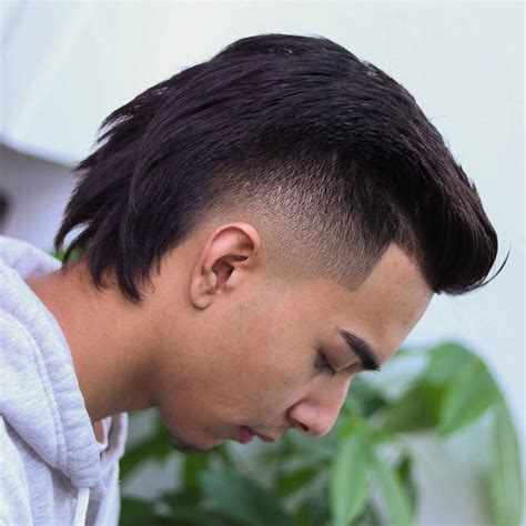 Burst fade with mullet. The disconnected mullet combines the edginess of a sharp contrast with the low burst fade’s gradual transition. This daring variation exudes a modern punk vibe, setting a bold statement with an unblended transition between the longer back and shortened sides. 