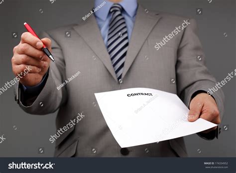 Businessmans hand holding a pen requesting a signature on a …