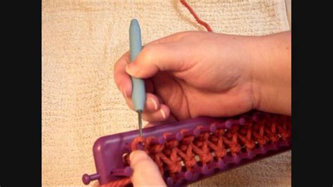 Step 2: Creating the Knit Stitch. Next, use the loom hook to lift the bottom loop from the first row up and over the. second loop. To lift the stitch, insert the hook up under the bottom loop, pulling the loop up and over the top yarn strand and up over the top of the peg. Drop it off the hook toward the inside of the loom.