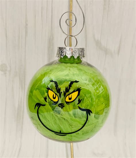 Cheap grinch ornaments. How to Make a DIY Grinch Ornament. First, gather your materials: Clear ornament (we used glass but if making with kids you can opt for plastic) Black Sharpie. Adhesive spray. Green glitter. Green feather. Pull up a picture of the Grinch’s face on your computer or phone, and let’s get started! Confidently draw the Grinch’s face with the ... 
