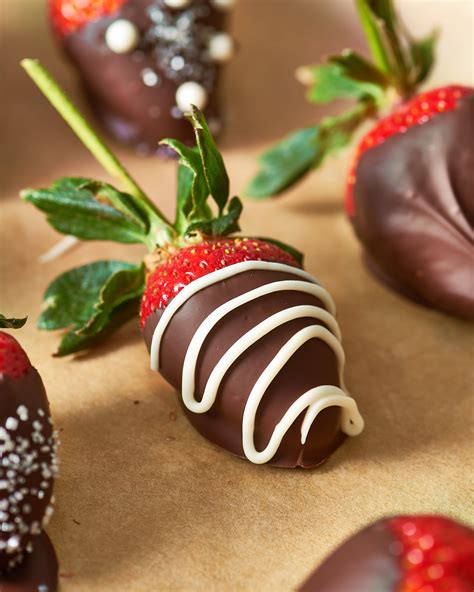 Cover tray with wax paper. Holding strawberry by top, dip 2/3 of each berry into chocolate mixture; shake gently to remove excess. Place on prepared tray. Refrigerate until coating is firm, about 30 minutes. Store, covered, in refrigerator. For best results, use within 24 hours. Coats about 5 dozen small strawberries.. 