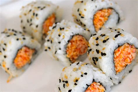 Crab sushi. Gently squeeze ~2 tablespoons of sushi rice in one hand in a long oval shape. Shape in a nigiri shape like below. Add a thin slice of salmon on top of the rice. Then, add on sliced avocado, spicy crab, teriyaki sauce, sriracha, sliced green onions, and sesame seeds. Repeat until all the salmon is used. 