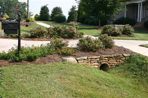 Culvert landscaping ideas. Blend Nature and Art. Blend natural and artificial elements to give your yard an established, comfortable look. For example, place boulders near the path and use groundcovers such as pachysandra. Flowering shrubs, such as azalea, rhododendron, and pieris, soften the look of the stone. 