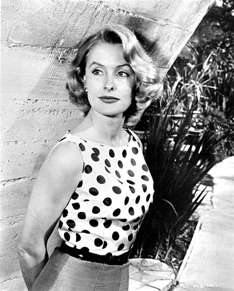 Actor Dina Merrill holding a sprig of leaves, against a backdrop of branches and lengths of chiffon, wearing a sleeveless pink dress with wide diagonal straps forming a shallow V-neck, by Grenelle-Estevez, and a blue and gold pin in the shape of two birds on a fruit-laden branch. Dina Merrill Joyce Rainboldt/CondÃ© Nast Special Instructions .... 