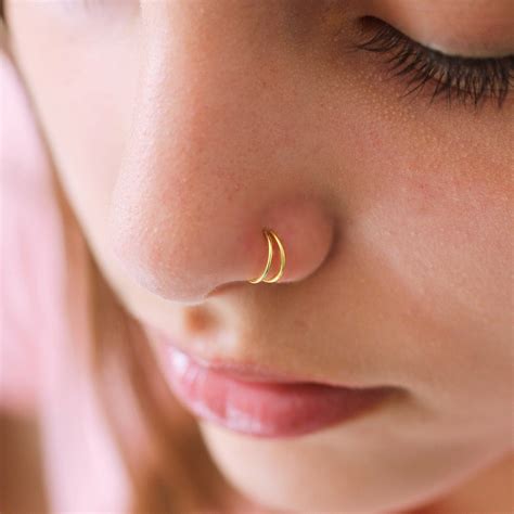 a double nose piercing done with a stud and a studded hoop will accent your face a lot. a cute nose piercing with studs, hoop earrings and layered necklaces for a party look. a double nose piercing done symmetrically with a hoop and a stud for a shiny look. a chic double nose stud piercing in one nostril and an additional septum hoop..