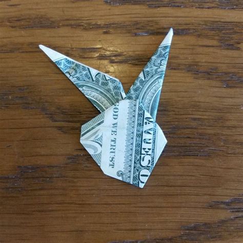 Easter origami dollar bill. STEP 2: On the left side, fold both corners to the half. Fold the lower left tip diagonally across evenly matching the left edge of the bill to the top edge. After creasing that fold, make a similar fold the opposite way and crease it. Open and flatten the bill once both folds are made. 