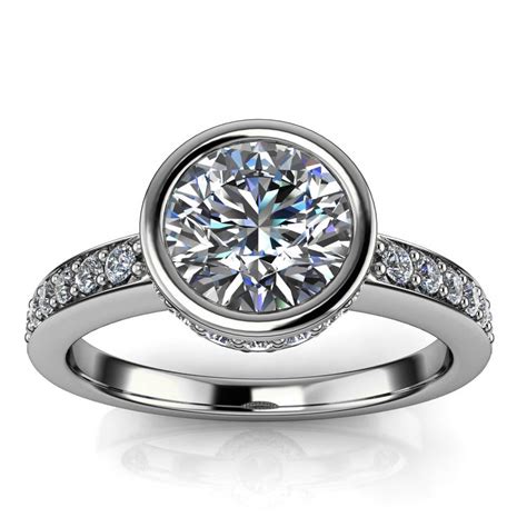 Engagement ring with bezel setting. A bezel set engagement ring is a unique, trend-forward setting choice for an engagement ring or a gift.While contemporary ring designs utilize claw or bead prongs to secure the center stone, bezel set engagement rings feature a border of precious metal that surrounds the center stone. 
