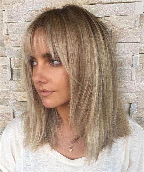 Styling Tips: Create beach hair waves using a large curling barrel, alternating the direction of the curls, to give hair that relaxed, tousled finish. Once the hair has cooled down, use your fingers to tease strands apart and make it messy. Beach waves should never be too perfect. 10. Layered long bob with bangs.. 