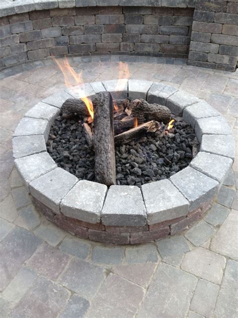 Fire pit from pavers. Make sure you check out the other image in this post as it’s a hardscaping dream. The pavers and tiles cover a large area comprising of a fire pit with a conversation set, a swimming pool, and a dining area. Large pavers set the scene for this reclaimed brick fire pit. The curved bench is made of oak sleepers. 