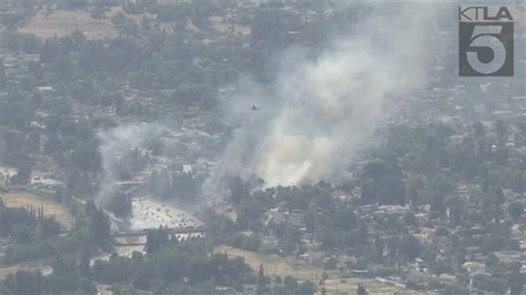 Firefighters battle brush fire near freeway in Granada Hills