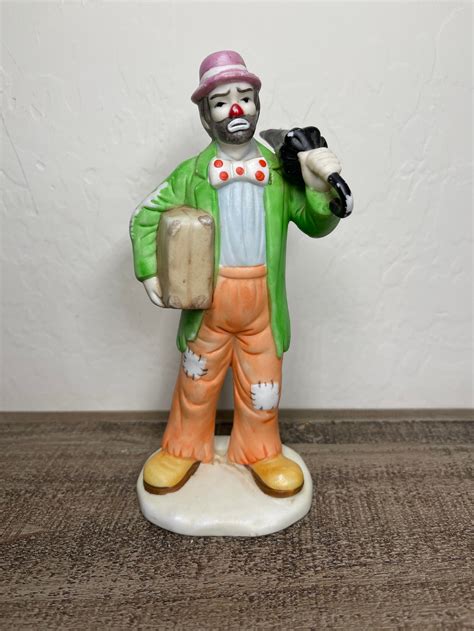Part of the Day At The Fair Collection. Limited issue 1373. Hand painted porcelain figure. Depicting Emmett the clown with two children in front of a haunted house entrance. Sits on a wooden base with gold-tone titled plaque. Emmett Kelly Jr. backstamp. Flambro hang tag and backstamp. Certificate of Authenticity included.