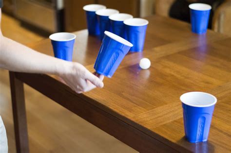Flip cup game. Drinking Game Name - flip cup variant. I saw a game the other day where 4 players were around a table with a grid on it and a shot glass in the middle. Each player flipped their cup and if successful pushes the shot glass forward one step on the grid to the player across them. 