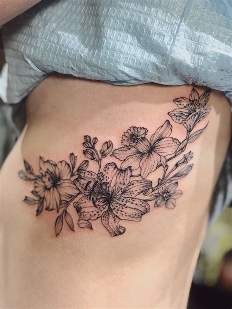 Beautiful floral tattoo design for the rib cage. Get inked with this stunning black and gray illustration. Perfect for those looking for a unique and artistic tattoo. #tattoo #ribcagetattoo #floral. 