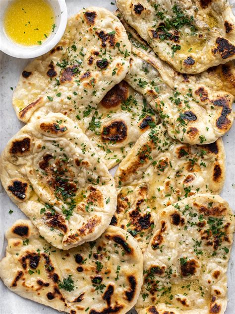 Garlic bread naan. Place the rolled out flatbread on it. Place a lid on the flatbread and cook for 2 minutes. Flip and cook for another 1 to 2 minutes. Place directly on the flame or grill to blacken, or continue to cook on the skillet until golden brown spots. Place on a serving plate and immediately brush with garlic herbed butter. 