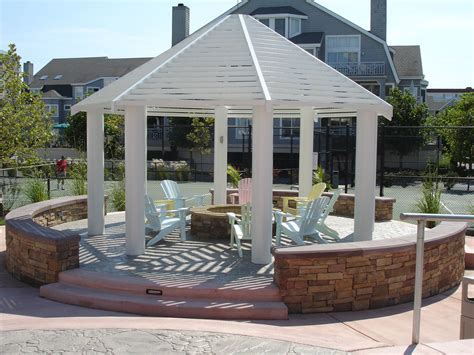 Gazebo with fire pit. Fire Pit With Inlaid Tile Rug. Leclair Decor. This spacious outdoor living room from Leclair Decor has comfortable wrap-around seating around a central rectangular fire pit that is positioned on top of an inlaid tile rug in a pale shade of gray to give it the feel of an indoor room. Continue to 12 of 30 below. 