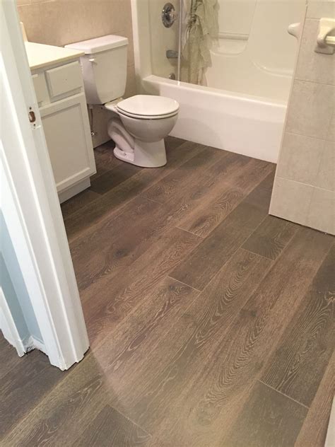Hardwood floor in bathroom. Omega Construction and Design, Inc. Mid-sized beach style 3/4 medium tone wood floor and brown floor bathroom photo in Other with flat-panel cabinets, white cabinets, white walls, an undermount sink and solid surface countertops. Save Photo. 11 Levels Transitional Colonial. 