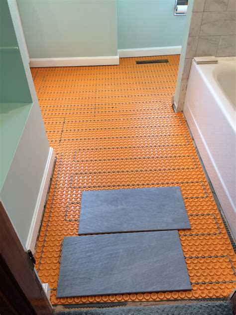 Heated bathroom floor. It is possible to put a rug on an underfloor heating system tile floor. As tile floor keeps the floor warm and doesn’t overheat, it doesn’t burn the rug over it. However, the choice of the rug is crucial to ensure an effective heating mechanism. A rug that is thin and breathable is the best. 