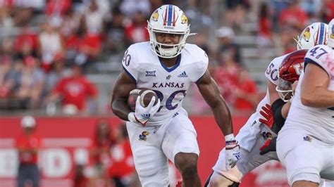 Kansas running back Daniel Hishaw Jr. (20) is stopped by several UCF defenders during the first half of an NCAA football game, Saturday, Oct. 7, 2023, in Lawrence, Kan. Credit: AP/Colin E Braley. 