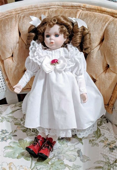 House of lloyd dolls. This stunning House of Lloyd 16" porcelain doll features blonde, curly hair and blue eyes with a light complexion. The doll is dressed in a Victorian Cinderella outfit and comes with a stand for display. The doll is an original from the House of Lloyd franchise and was manufactured in the 1980s. It is in its original packaging, although the packaging has been opened. 