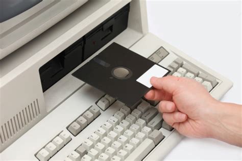 How to make a floppy disk.  Hand inserting floppy disk into old desktop comp...