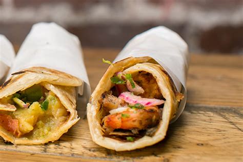 Kati roll company. Sprinkle half the chaat masala over the egg surface followed by a sprinkle of salt. Place half of the pickled red onion on the paratha. Place it in the center, in a line running down the middle of the paratha. Top the red onions with the half the tomato chutney or achaar. Top with the green onions. 