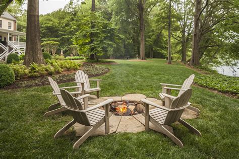 Landscaping fire pit. The Square Fire Pit. A tranquil forest backdrop sets the tone for this backyard fire pit, creating an intimate gathering spot. The stacked stone fire pit is surrounded by outdoor wicker furnishings. (via Alderwood Landscape Architecture) 12. Fire Pit Wall. A low stone wall is curved around the fire pit. 