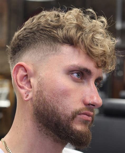 The Textured Crop Top Fade is a modern, tapered haircut that combines a blunt fringe on the top with a fade on the sides and back, creating a masculine and rugged look. This low-maintenance hairstyle is perfect for men with receding hairlines, as it helps hide the hairline while adding texture and volume with the help of matte pomade or wax.. 
