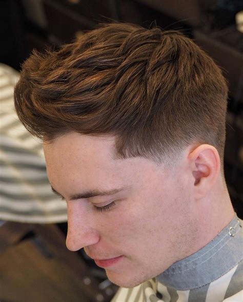 Low taper fade with a textured fringe. #3: Low Fade with Thick Textured Fringe. The low fade with thick textured fringe is a stylish and versatile hairstyle for men. The longer hair on top has a textured finish, adding volume and a rugged appeal. This haircut works well for men with thick hair, allowing easy styling. 