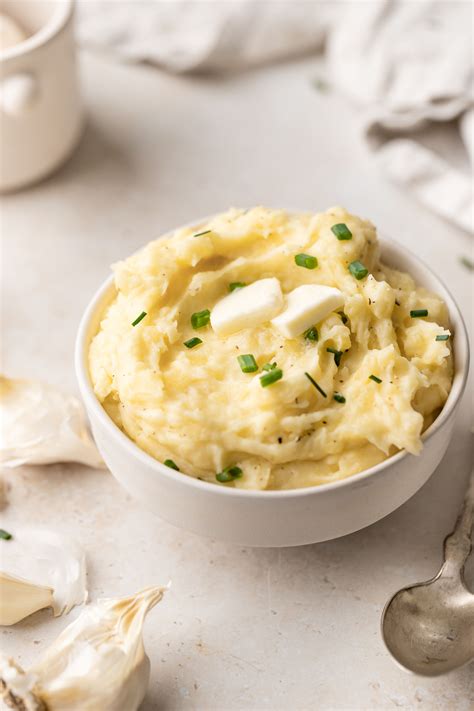 Put potatoes in a pot, cover with cold water and boil 15-18 minutes or until easily pierced. Warm the milk – when potatoes are nearly done cooking, in a small saucepan, combine milk and smashed garlic. Heat just until steaming then remove from heat. Drain the potatoes and keep them in the same pot to mash.. 