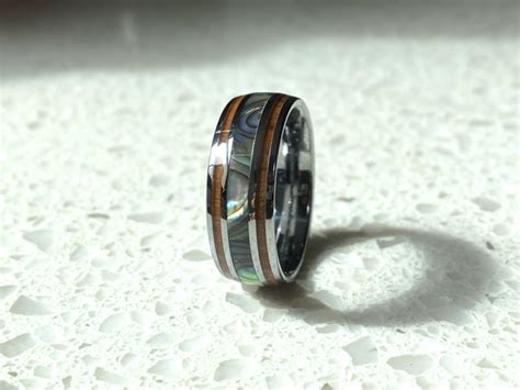 Manley bands. This ring'll give you history in the palm of your hand, and you didn't even have to extract DNA from a mosquito / almost ruin the world to get it! Black Zirconium (charcoal gray color) with 5mm Genuine Black Dinosaur Bone Inlay and Desert Ironwood Sleeve. 9mm Wide. Domed Design in Comfort Fit with Rock Polished Finish. 