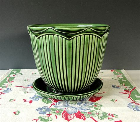 This vintage McCoy USA ceramic planter is a beautiful example of post-war design. The glossy green finish is etched with intricate details and measures about 7 inches in diameter. Made in the mid-20th century, this piece is from the era of 1940-1949 and is perfect for all occasions.