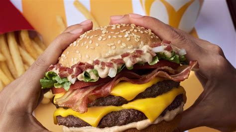 Mctasty. Double Big Tasty™Bacon. Two patties made from 100% beef, 3 slices of melted cheese with fresh tomato, fresh onion, bacon, iceberg lettuce, the delicious Big Tasty™ sauce in a soft, sesame seed bun. 